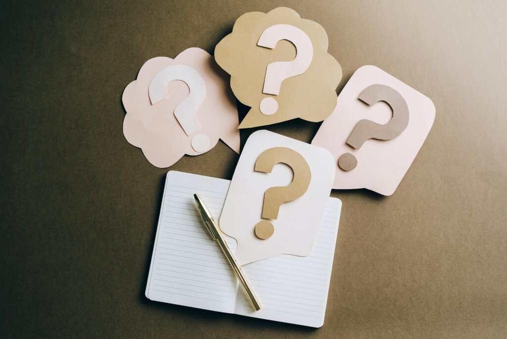 Starter Website vs. Business Website: Which One Does Your Company Really Need? Flat lay of question mark paper crafts on a notebook, symbolizing questions and ideas.